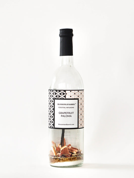 Bottle of Grapefruit Paloma cocktail mix with decorative elements on a white background