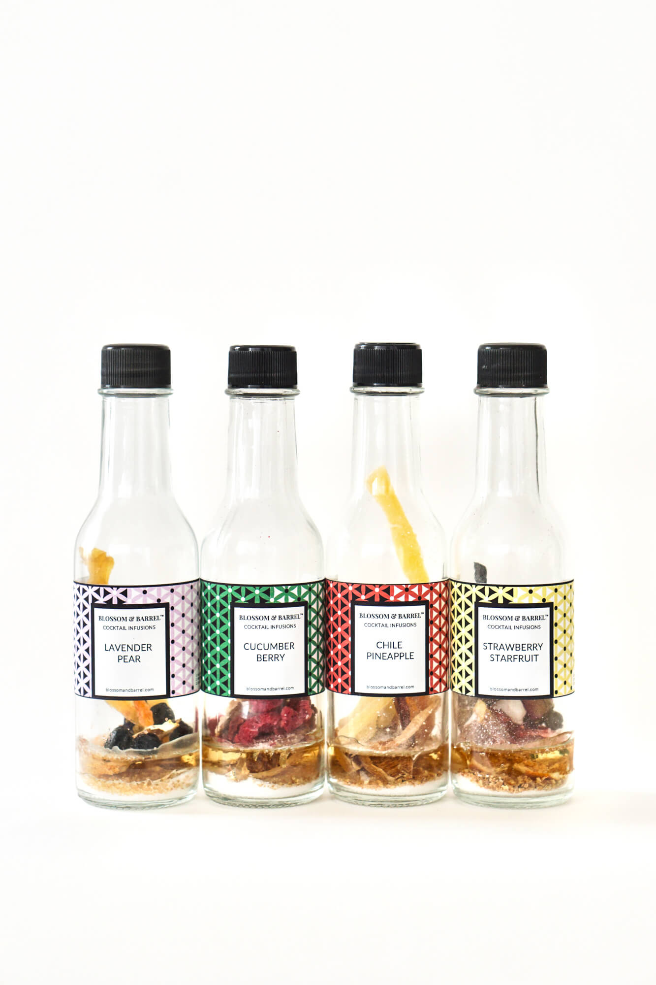 Four bottles of flavored cocktail mix with colorful labels on a white background